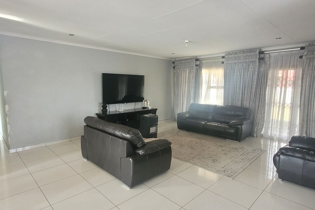 Spacious living room featuring large format floor tiles, recessed downlighting, and direct access to the exterior through sliding glass doors.