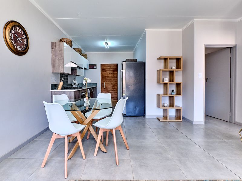 Modern open-plan living area featuring a compact kitchen with built-in cabinetry, tiled flooring, and a functional layout suitable for dining and daily living.
