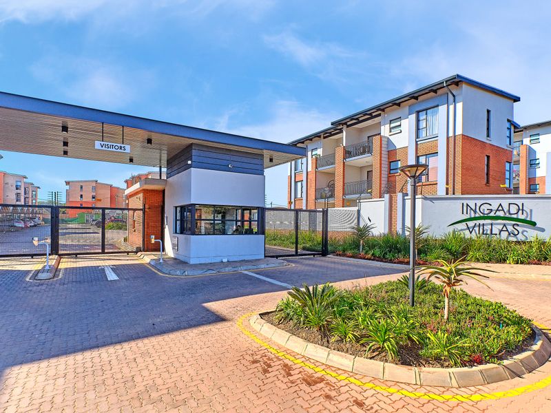 The main entrance to Ingadi Villas featuring a secure guard house, automated vehicle access gates, and well-maintained paved driveway and landscaped garden areas.