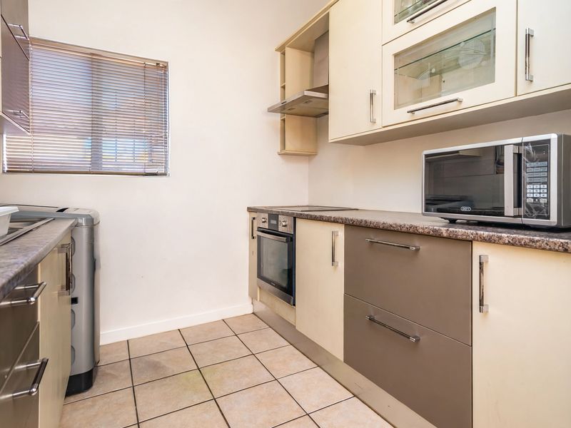 A functional kitchen featuring built-in cabinetry, laminate countertops, a built-in oven, extractor fan, and ceramic floor tiles.