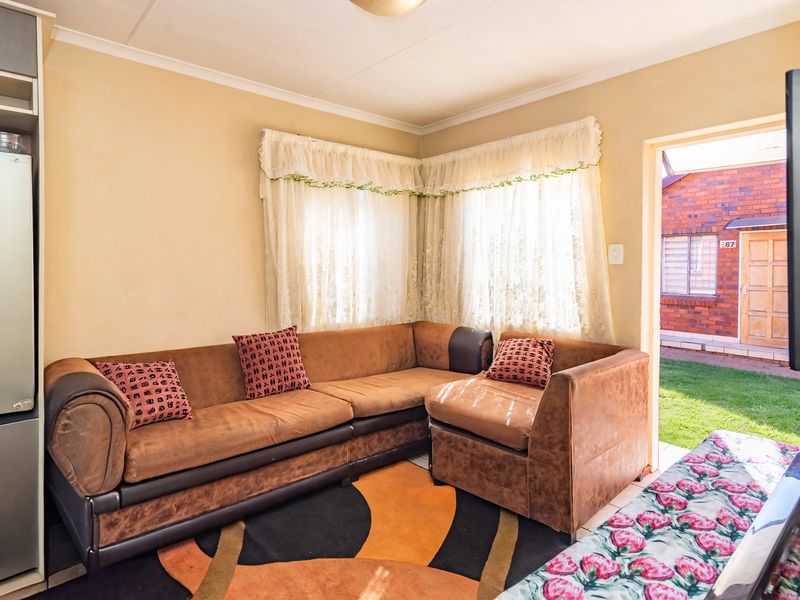 A compact living room area featuring a built-in cupboard and direct access to the exterior garden space.