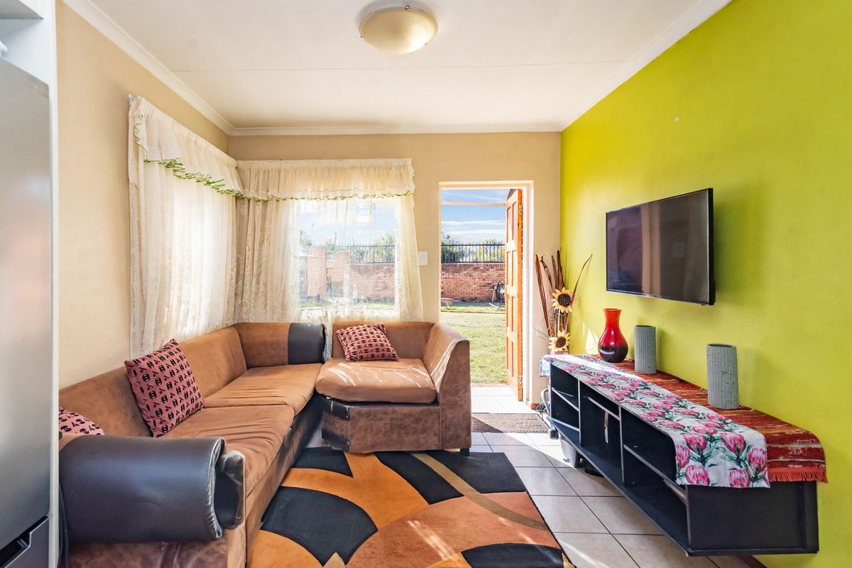 A living room featuring tiled flooring and direct access to the rear garden through an external door.
