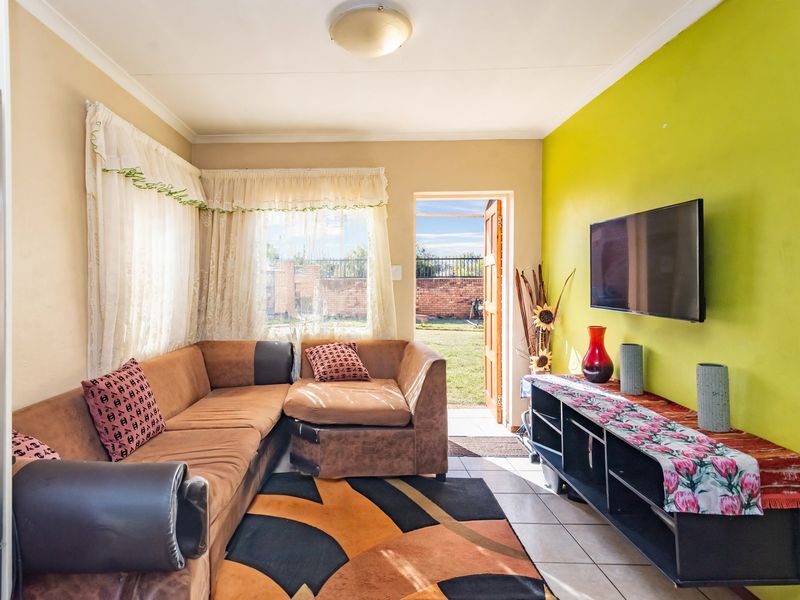 A living room featuring tiled flooring and direct access to the rear garden through an external door.