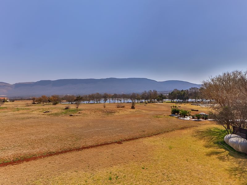Expansive scenic view overlooking open fields, mature trees, and distant mountains, providing a peaceful and natural outlook from the property.