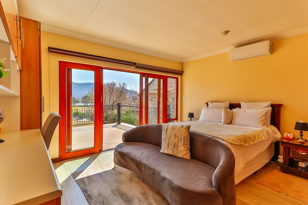 Spacious bedroom featuring built-in cabinetry, laminate flooring, and large sliding glass doors opening onto a private balcony with scenic views.
