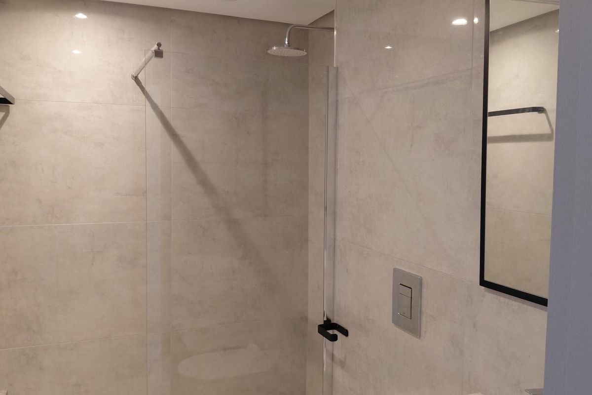 Modern bathroom featuring a walk-in shower with a glass screen, rainfall showerhead, and contemporary matte black fixtures.