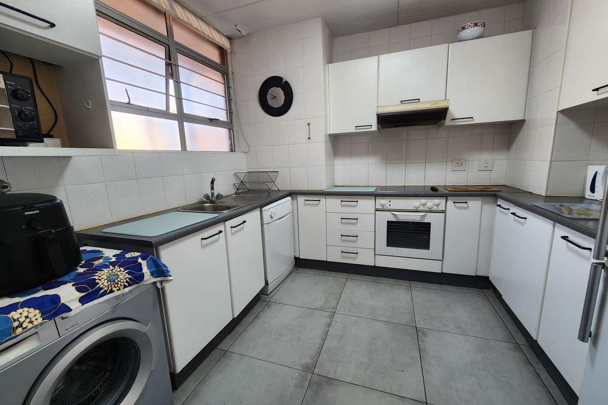 A functional kitchen featuring white cabinetry, tiled splashbacks, built-in oven and hob, and space for under-counter appliances.