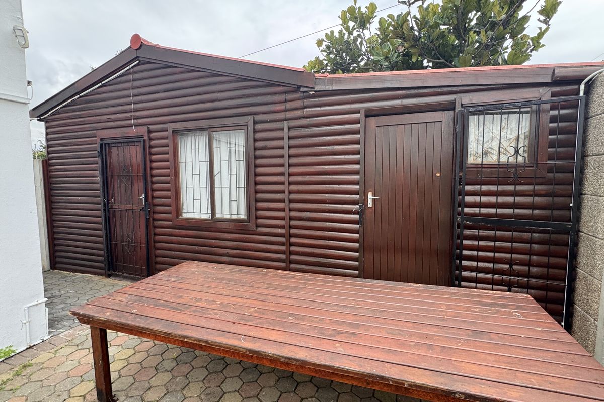 Exterior view of a timber log cabin structure featuring security gates and paved outdoor area.