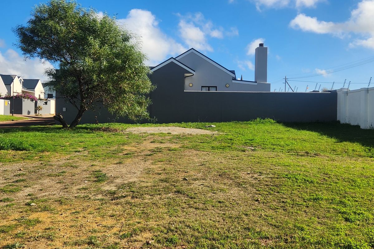 A vacant residential plot featuring established perimeter walls and electric fencing, offering a clear space for future development.