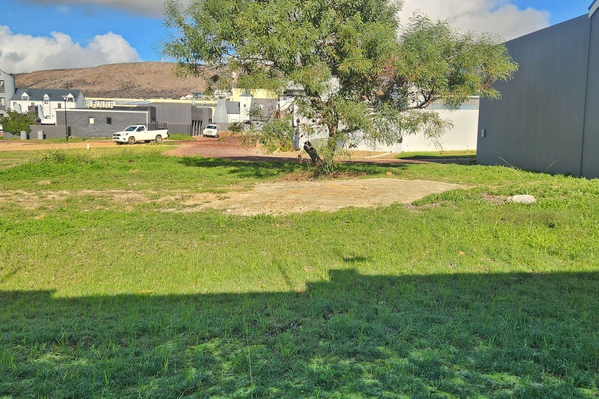 A view of a vacant residential plot featuring a grass lawn and a concrete slab foundation area.
