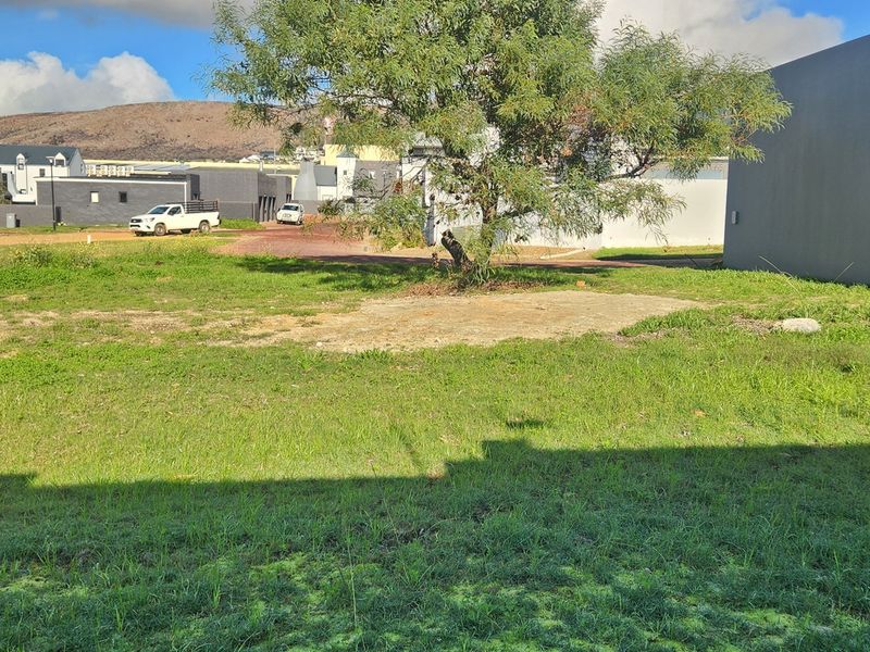 A view of a vacant residential plot featuring a grass lawn and a concrete slab foundation area.