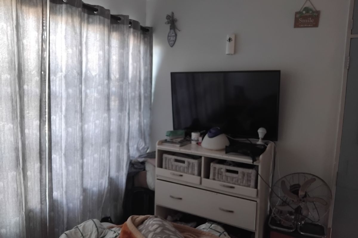 A bedroom interior featuring a window with curtains and wall-mounted electrical fixtures.