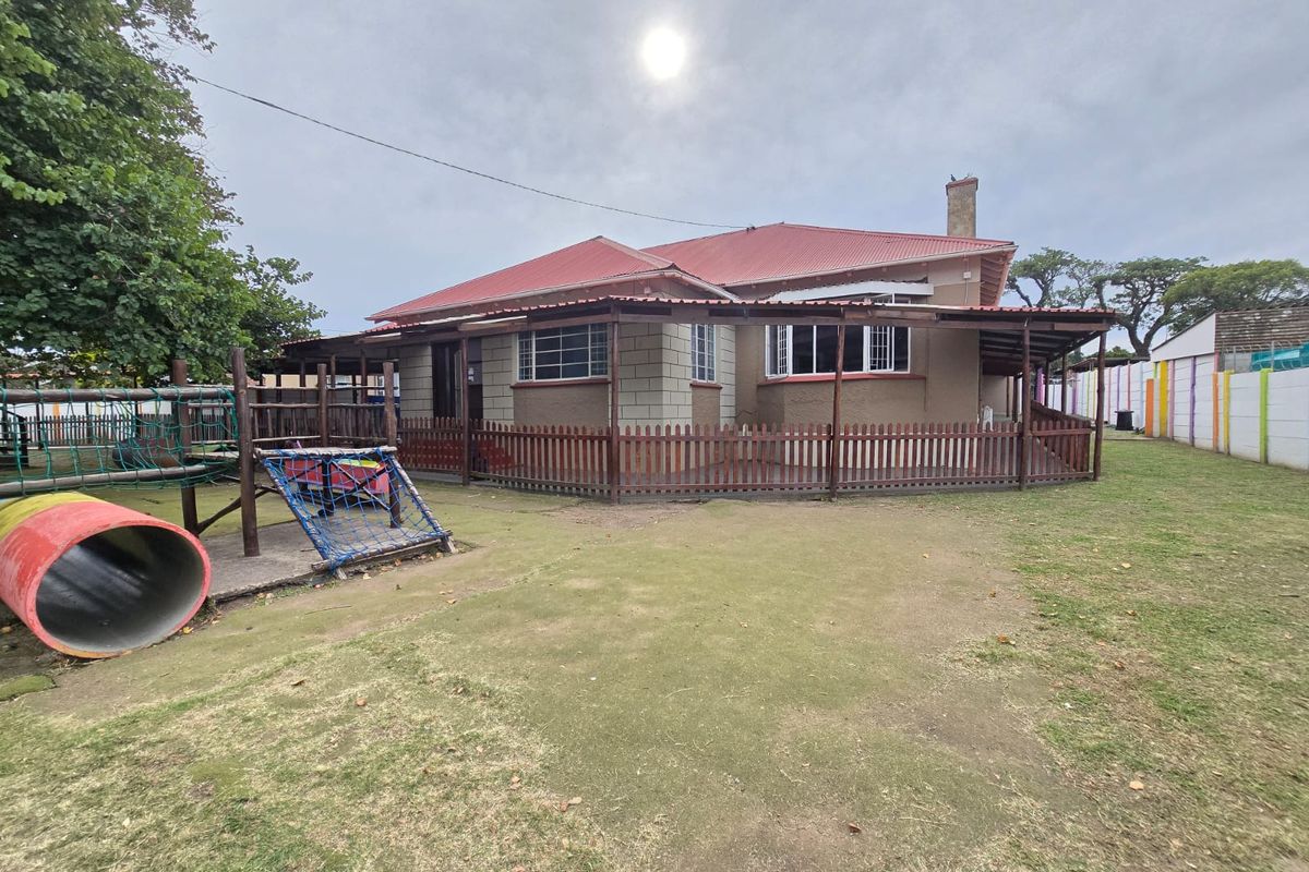 Rear view of the property featuring a covered patio area, brick and rendered exterior walls, a red metal roof, and a large garden space.