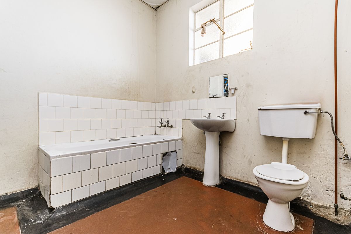 A dated bathroom featuring a standard bathtub, pedestal basin, and toilet, requiring significant renovation and cosmetic updates to improve its condition.