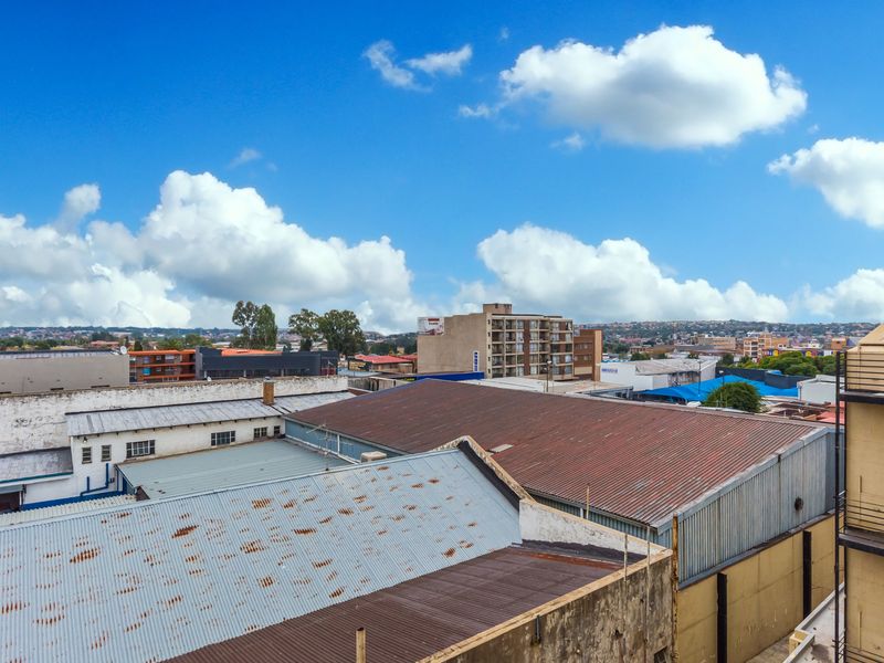 An elevated urban view overlooking surrounding industrial and residential rooftops under a clear blue sky.