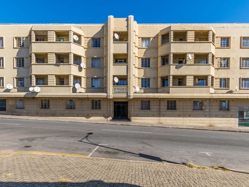 Front elevation of Olivanna Mansions, an apartment building featuring Art Deco architectural elements, multiple balconies, and street-level access.