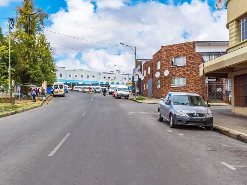 A street-level view of the urban neighborhood surrounding the property, featuring brick apartment buildings and local road infrastructure.