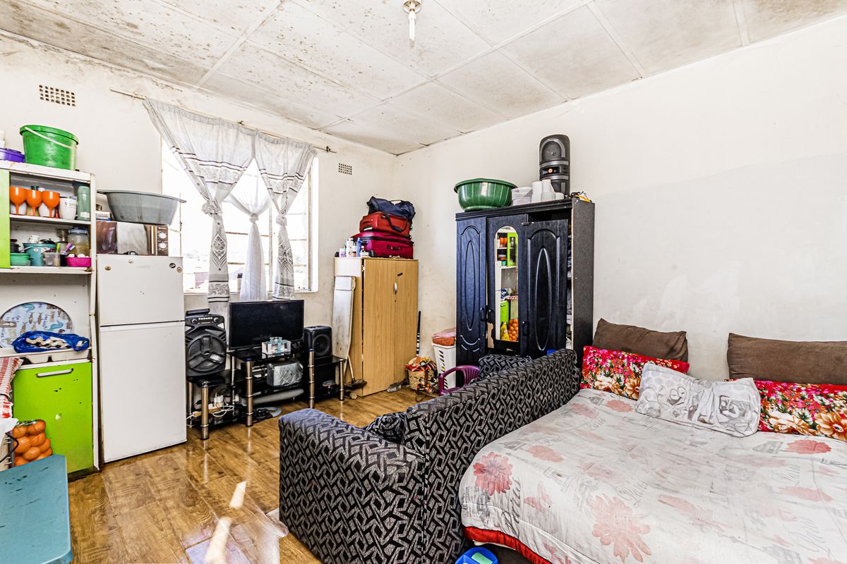 A living area featuring laminate flooring and ceiling tiles, currently showing significant signs of wear and requiring maintenance or renovation.