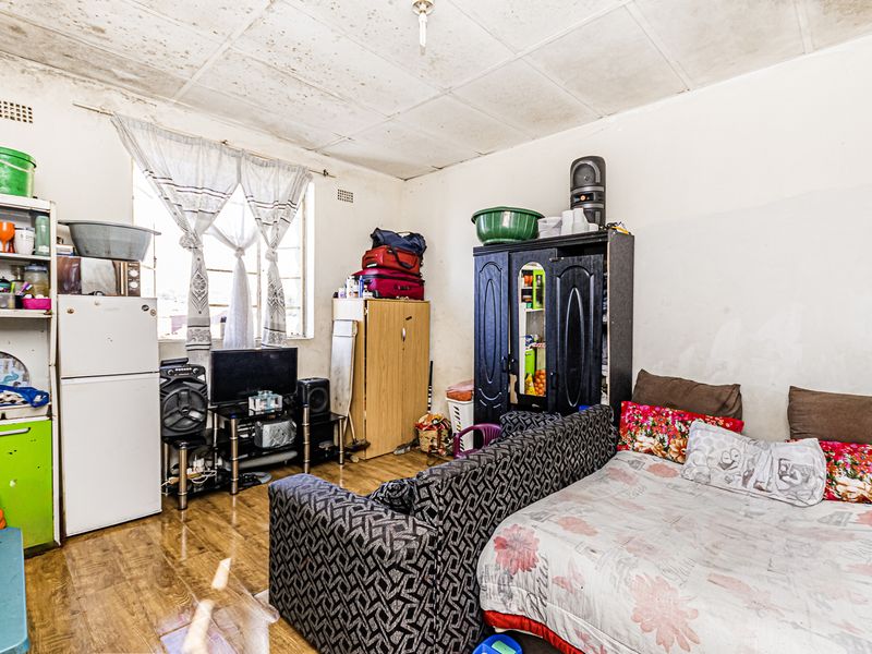 A living area featuring laminate flooring and ceiling tiles, currently showing significant signs of wear and requiring maintenance or renovation.