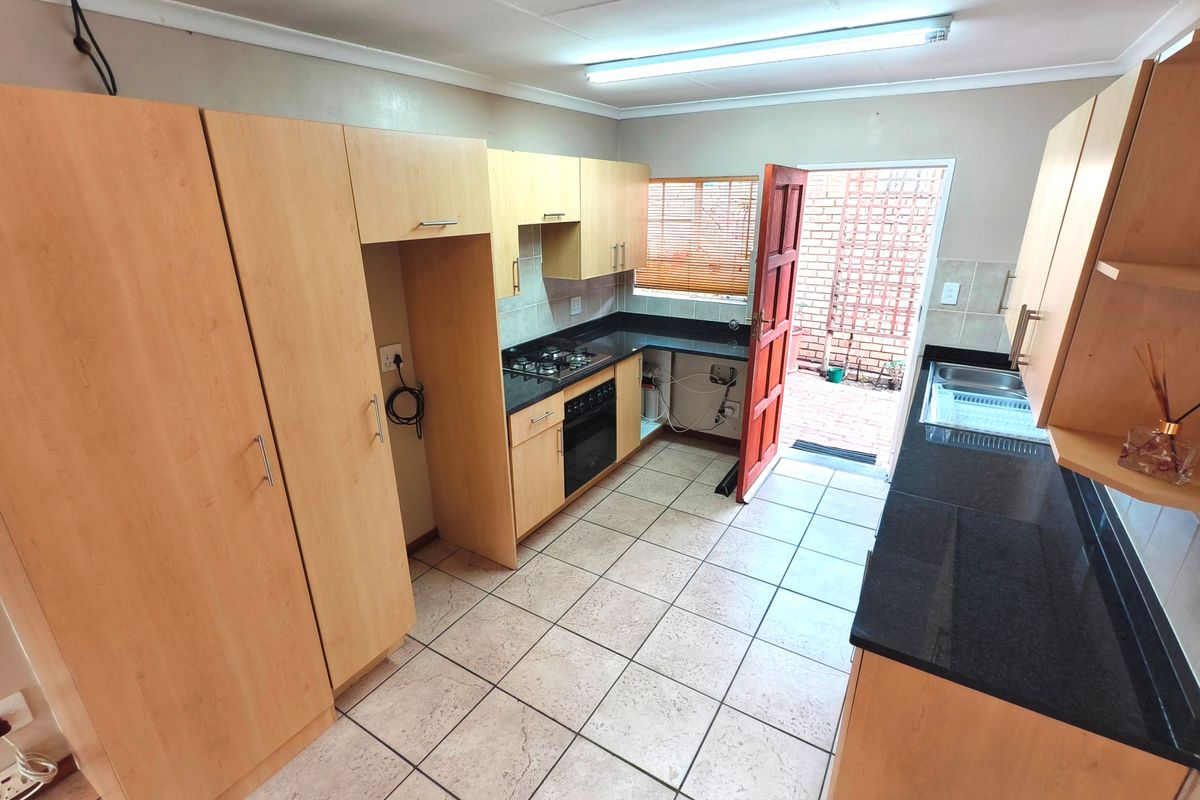 Functional kitchen featuring light wood cabinetry, dark granite countertops, built-in oven and hob, and direct access to an outdoor area.
