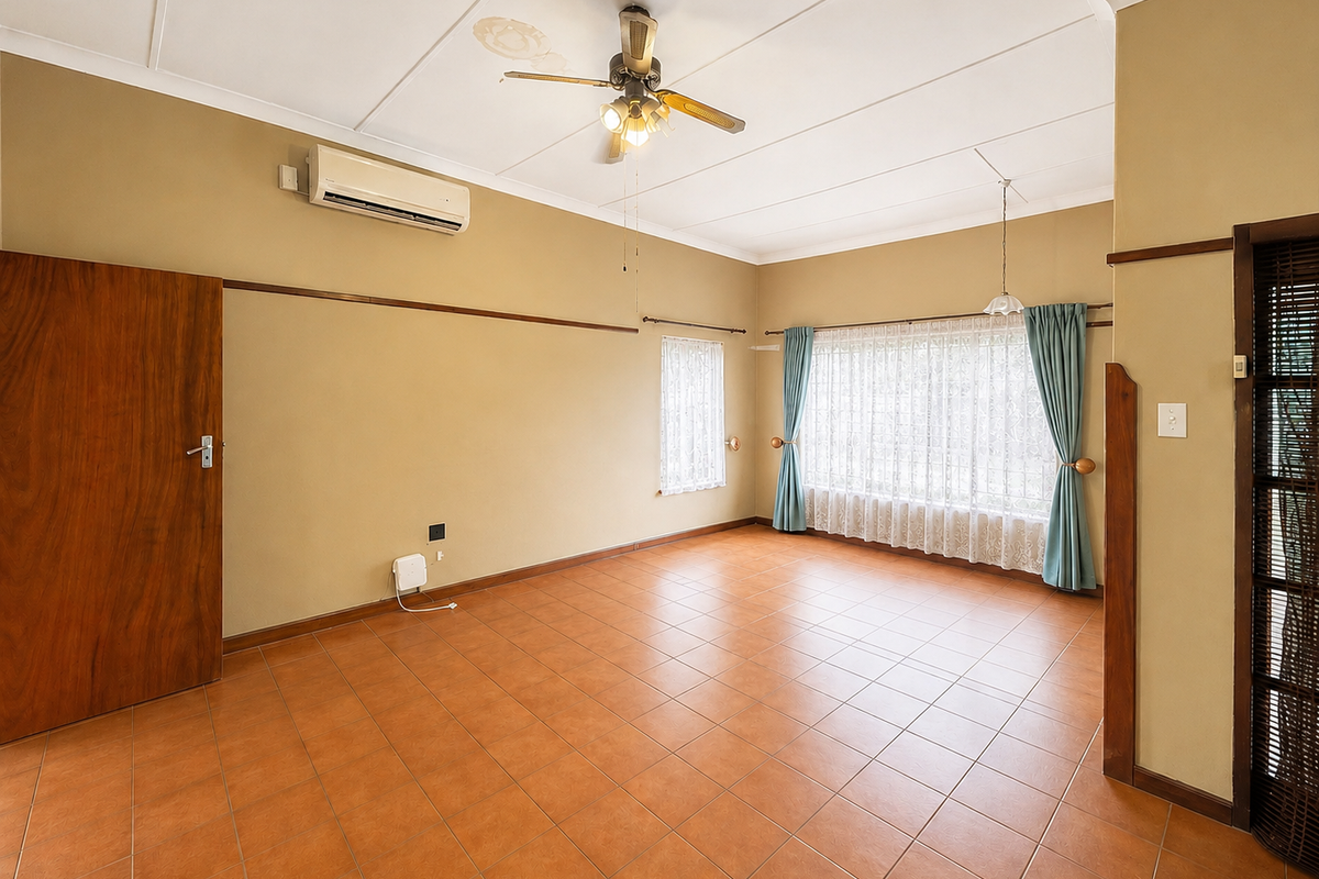 Spacious living area featuring tiled flooring, a ceiling fan, and a wall-mounted air conditioning unit, offering a neutral canvas for personalization.
