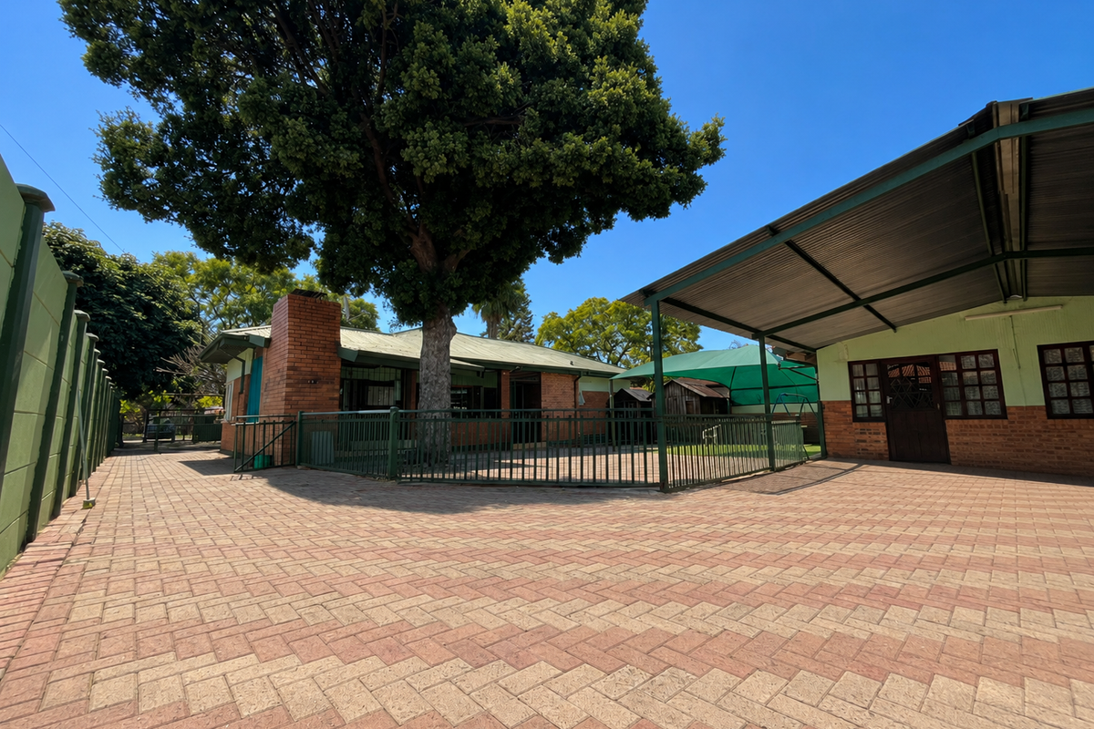 Spacious rear courtyard featuring extensive brick paving, a large covered carport area, and established trees, providing a functional outdoor space.