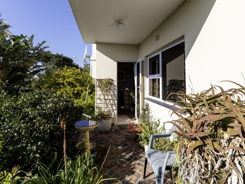 A covered brick-paved patio area adjacent to the garden, featuring an entrance door and access to the interior living space.