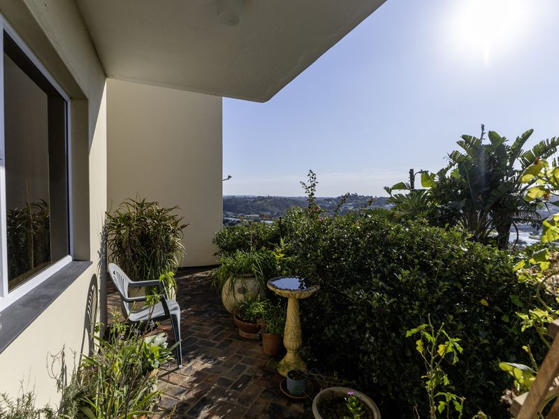 A covered balcony featuring brick paving and a scenic elevated view, providing a pleasant outdoor space for relaxation.
