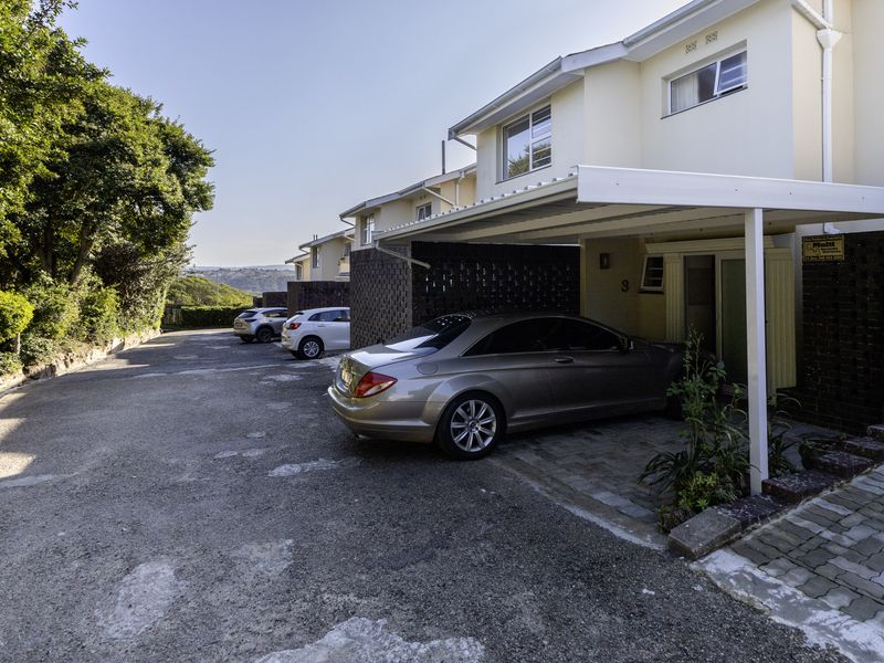 Front exterior view of the townhouse featuring a covered carport, paved driveway, and brick facade detailing.