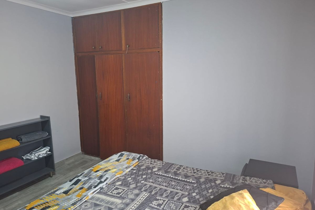 A bedroom featuring built-in wooden wardrobes and tiled flooring, offering a functional space with neutral wall tones.