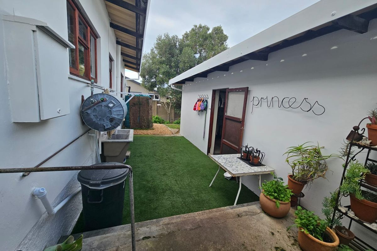 A functional side courtyard area featuring artificial turf, a concrete utility sink, and direct access to the property's exterior.