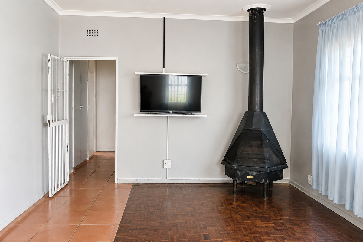 Living room featuring a freestanding black metal fireplace, parquet flooring, tiled transition area, and a security gate leading to the hallway.