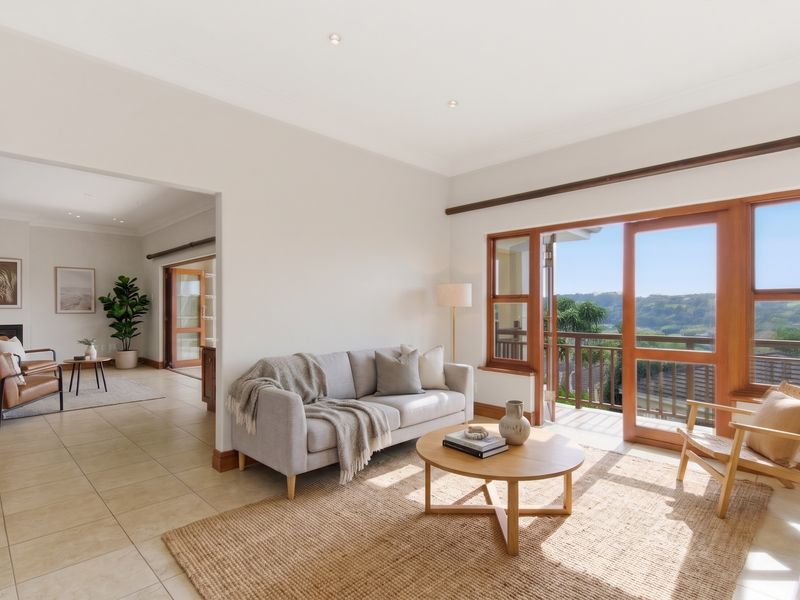 Bright and airy living room featuring tiled floors, recessed lighting, and timber-framed glass doors opening onto a balcony with scenic views.