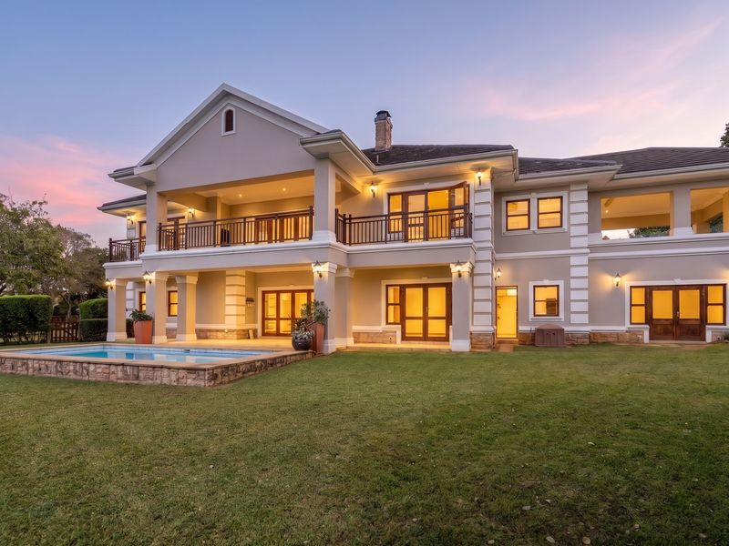 Stunning rear elevation of a luxury townhouse featuring a swimming pool, expansive lawn, upper-level balcony, and elegant architectural detailing with warm exterior lighting.