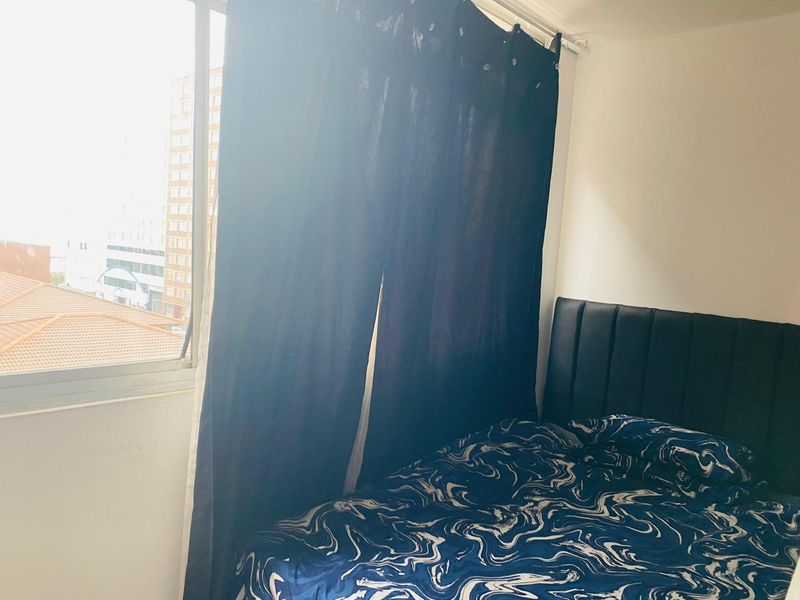 A bedroom featuring a window with natural light and a view of the surrounding urban area.