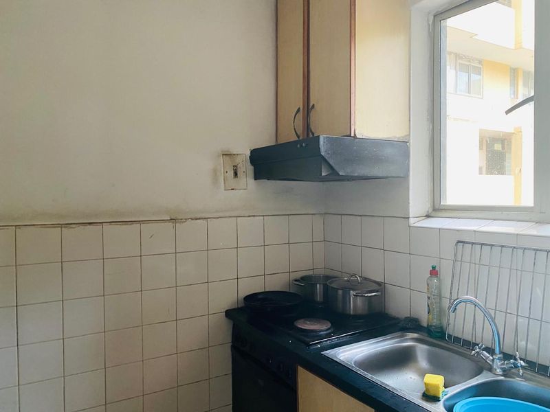 Compact kitchen area featuring built-in cabinetry, a stainless steel sink, and an integrated stove with an extractor fan.