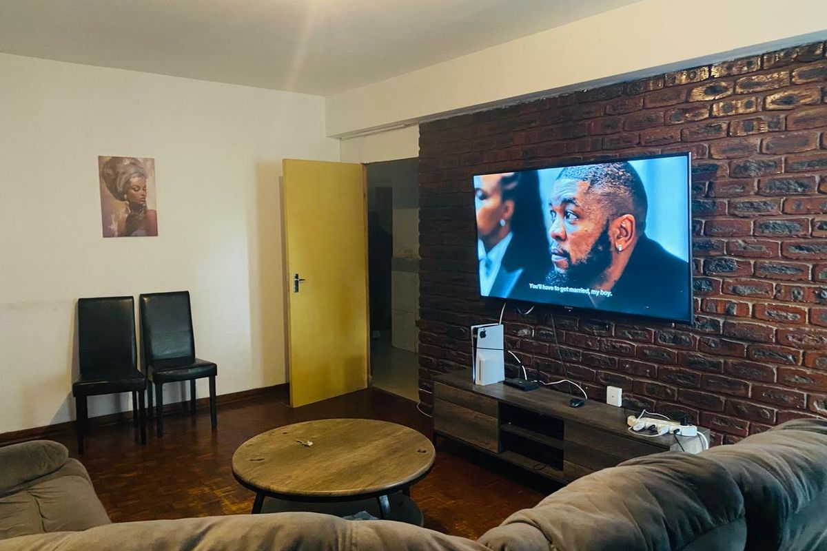 Living room featuring a prominent exposed brick feature wall, parquet flooring, and a doorway leading to an adjacent space.