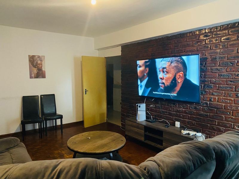 Living room featuring a prominent exposed brick feature wall, parquet flooring, and a doorway leading to an adjacent space.