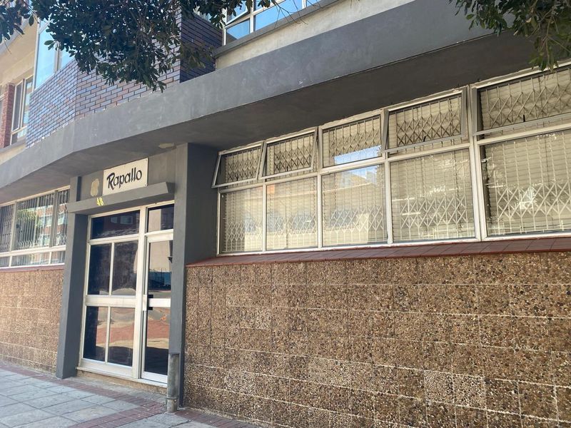 Front entrance view of the Rapallo apartment building, featuring a pebble dash facade, aluminium window frames, and security gates.