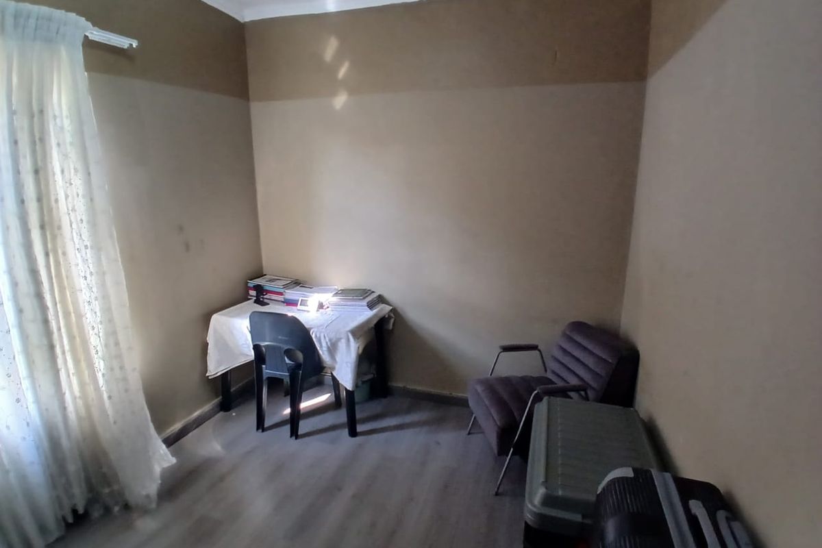A compact bedroom featuring wood-look laminate flooring and neutral wall tones, suitable for use as a home office or guest room.