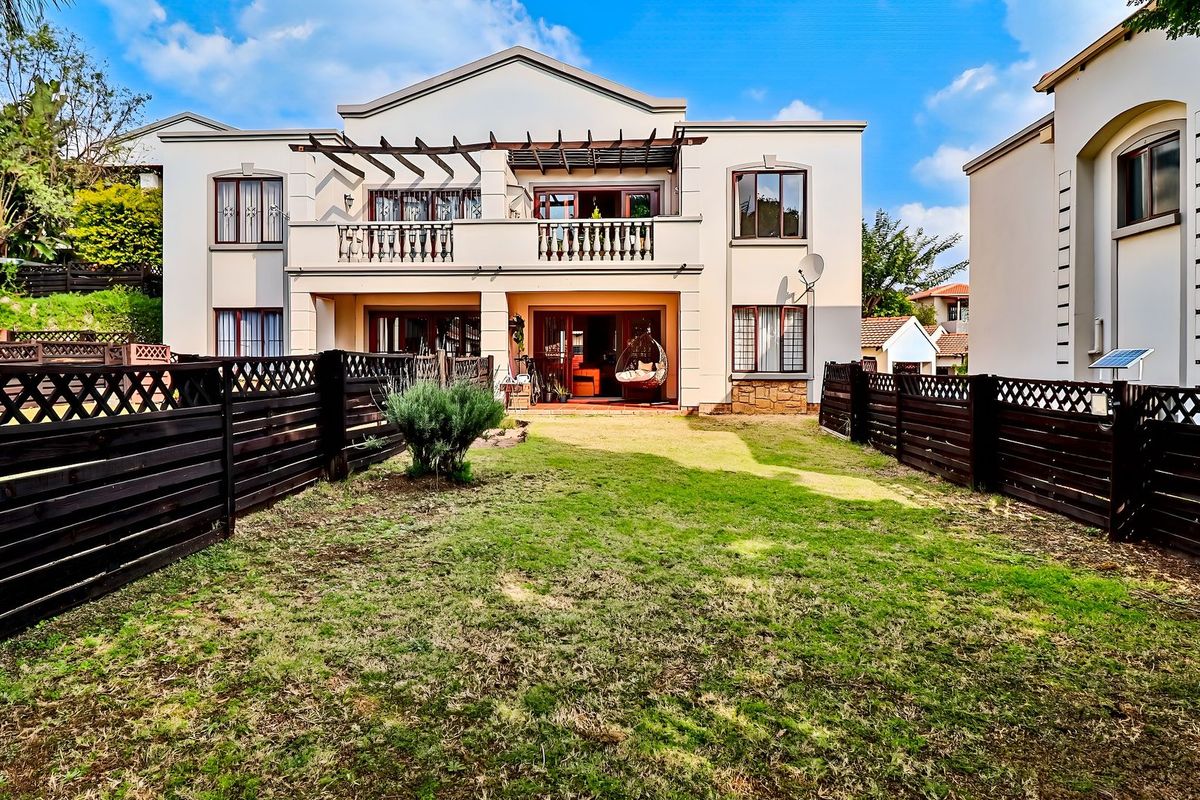 Rear view of the townhouse featuring a private garden, timber fencing, and a covered balcony with a pergola structure.