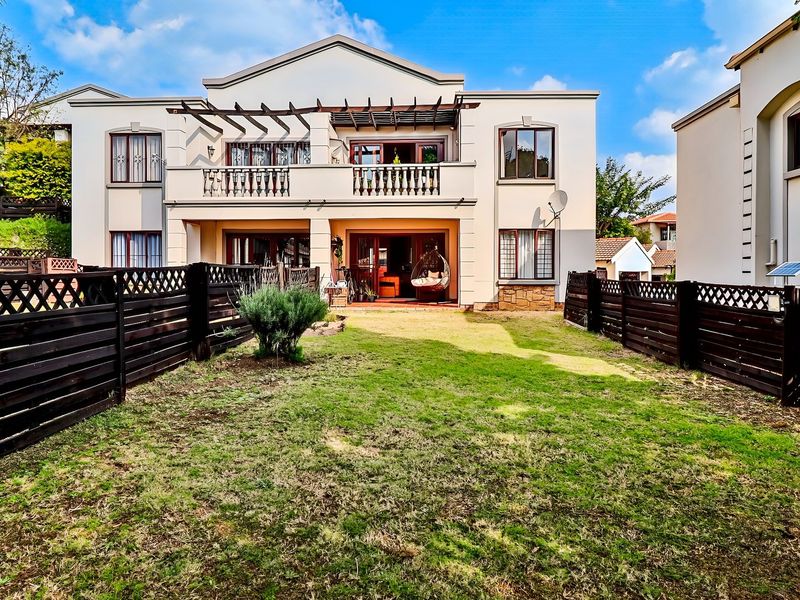 Rear view of the townhouse featuring a private garden, timber fencing, and a covered balcony with a pergola structure.