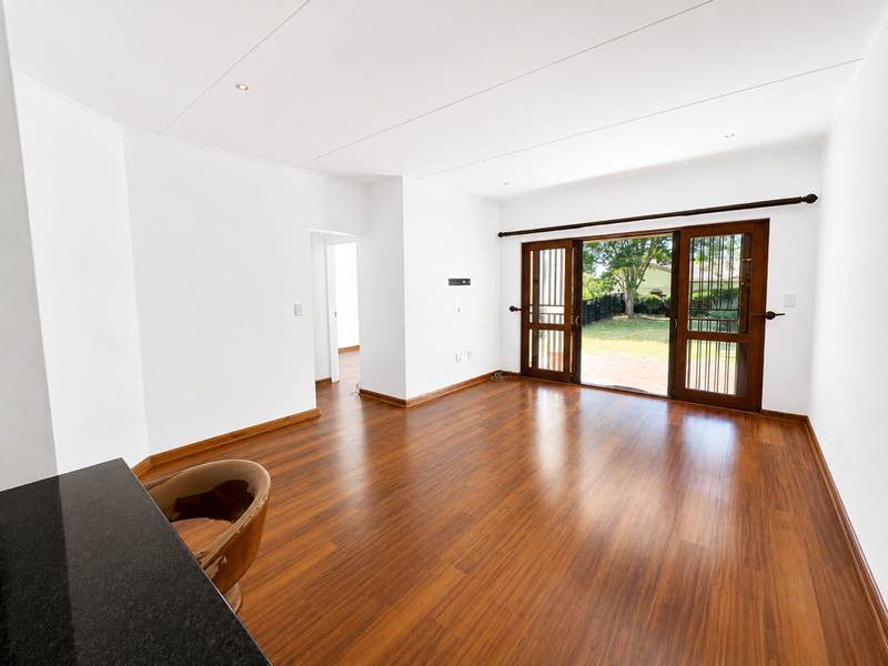 Spacious living area featuring warm laminate flooring, recessed lighting, and large wooden sliding doors providing direct access to the rear garden.