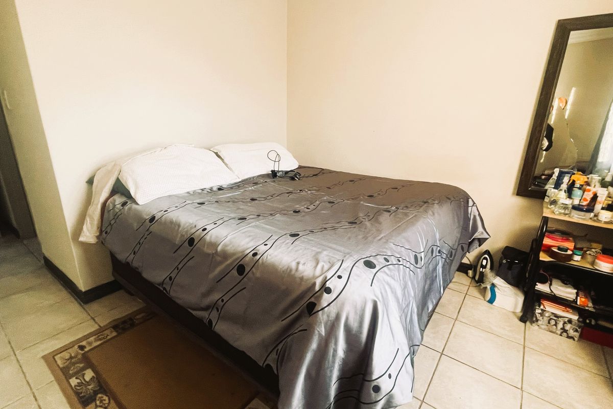 A bedroom featuring tiled flooring and neutral wall finishes, providing a functional space for rest.