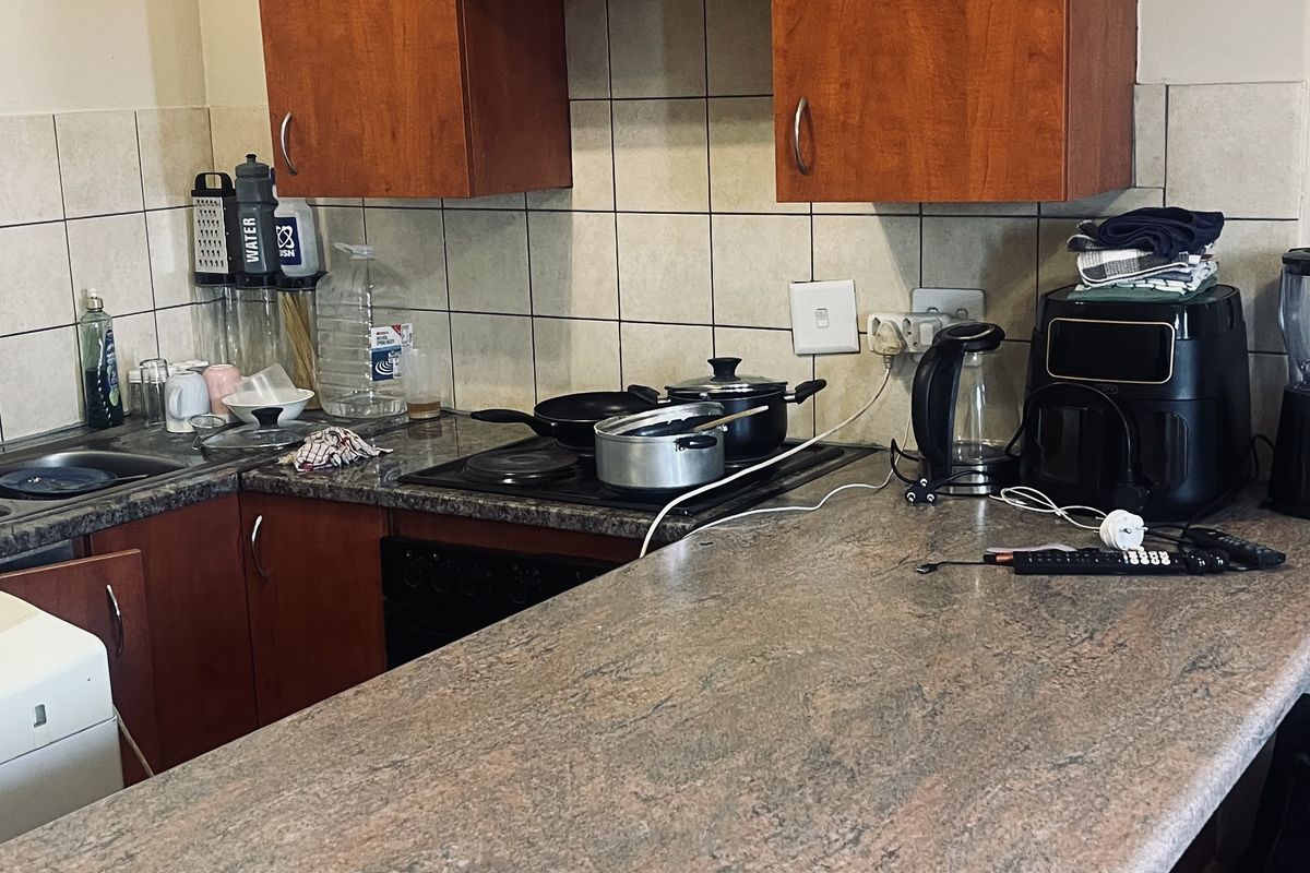 A functional kitchen featuring wood-look laminate cabinetry, stone-patterned laminate countertops, and a tiled backsplash, providing a practical workspace for daily cooking.