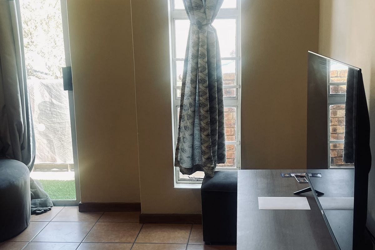 A living area featuring tiled flooring, a vertical window, and a sliding glass door providing access to an outdoor space.