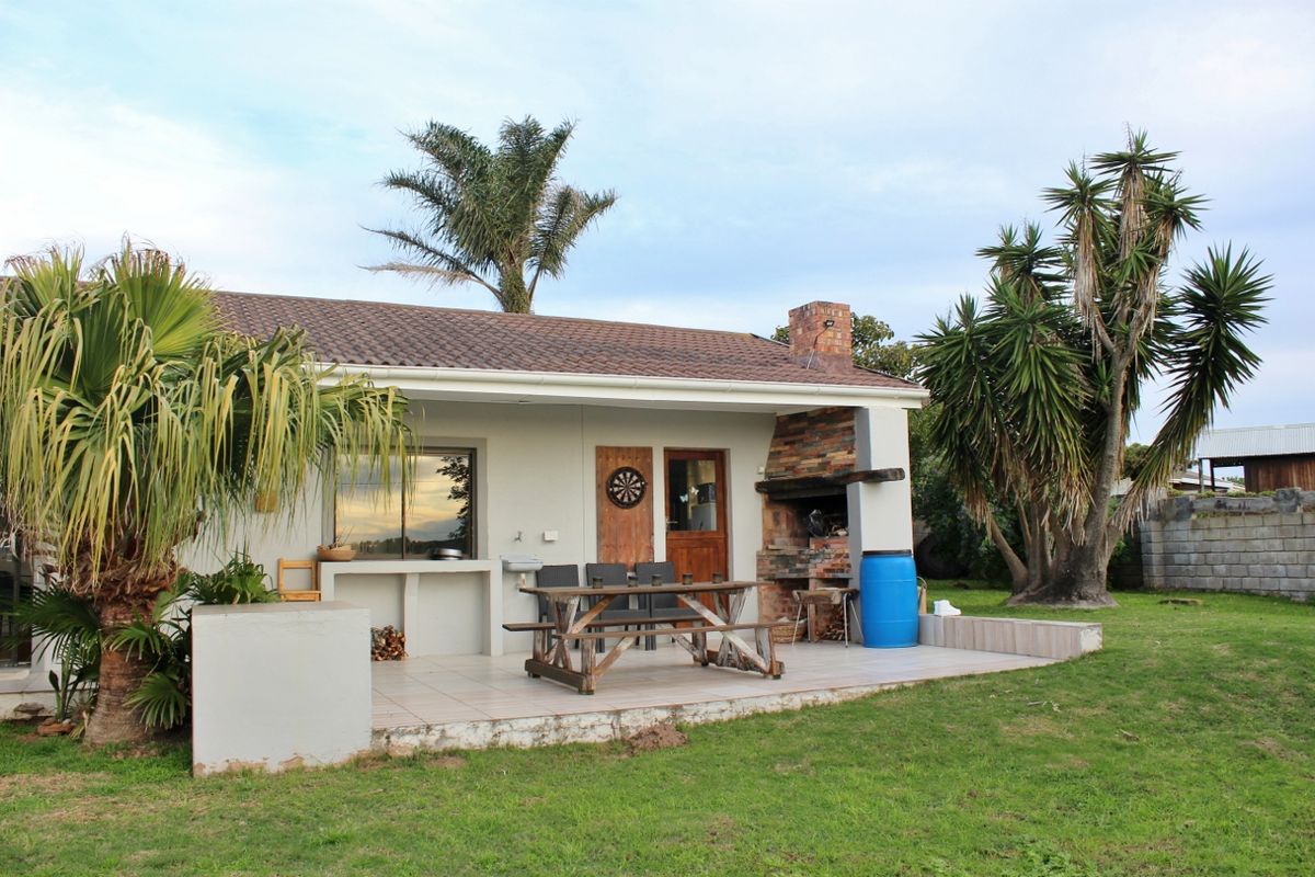 Covered outdoor patio area featuring a built-in brick fireplace, tiled flooring, and direct access to the rear garden.