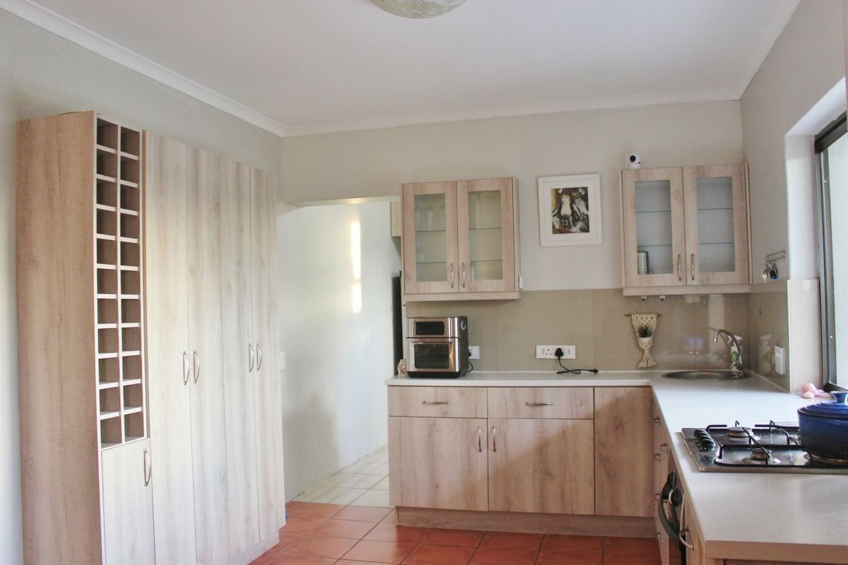 A functional kitchen featuring light wood-grain cabinetry, a built-in gas hob, and tiled flooring, offering ample storage and a clean, practical layout.
