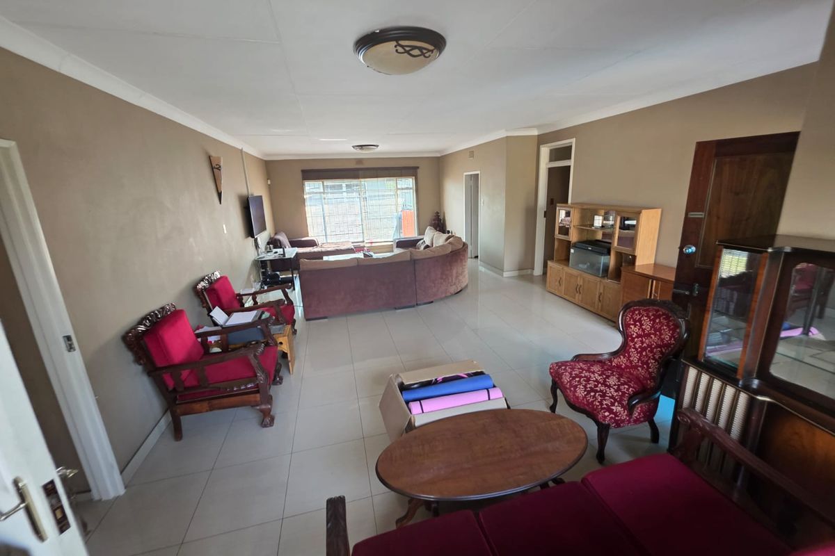 Spacious open-plan living area featuring large format floor tiles, neutral wall tones, and ample natural light from the rear window.