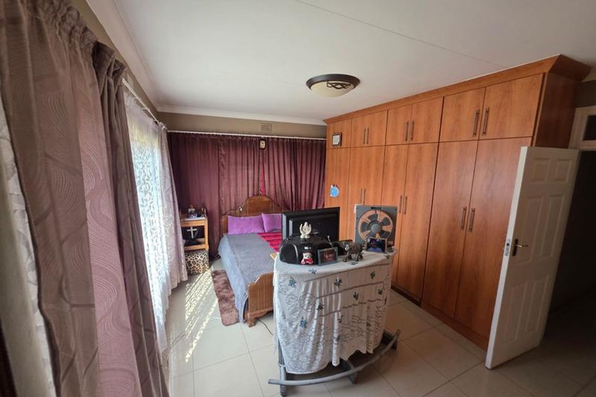 A bedroom featuring extensive built-in wooden cabinetry, tiled flooring, and a ceiling-mounted light fixture.